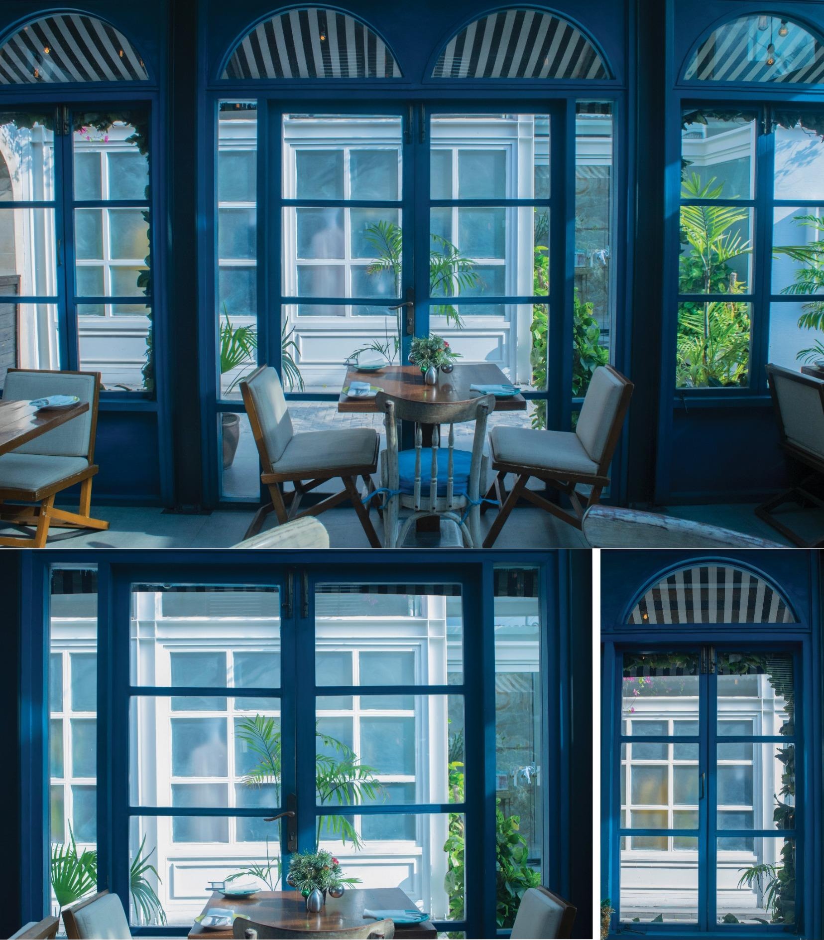 Blue-painted French windows and cane chairs around a small table in a bright courtyard room