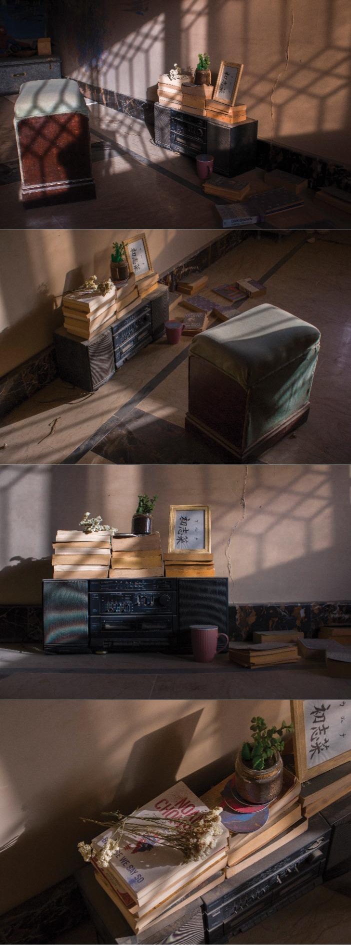 Four frames of stacked books, a framed photograph and a cushion on the floor in shifting afternoon light